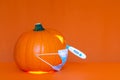 Side view Halloween pumpkin head jack lantern wears face mask the temperature is measured trendy orange background Royalty Free Stock Photo