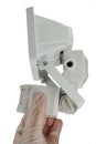 Side view of halogen security light with motion sensor, white finish, held in hand in transparent latex glove, white background.