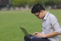 Side view of handsome Asian business man working with laptop on the green grass. Royalty Free Stock Photo