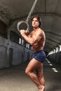 A handsome gymnast with muscular body posing with gymnastics rings in the abandoned industrial building Royalty Free Stock Photo