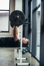 side view of handsome athletic man lifting barbell with weights while lying on bench Royalty Free Stock Photo