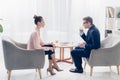 Side view of handsome businessman giving interview to journalist and drinking tea Royalty Free Stock Photo