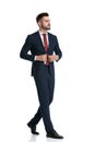 Handsome businessman walking while fixing his jacket with style Royalty Free Stock Photo