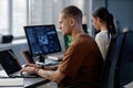 Profile of Focused Male Programmer with Septum Coding on Laptop at Working Desk in Office