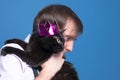 Handsome man in shirt holding on sholder black cat in pink shiny crown on blue background