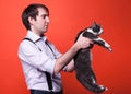 Handsome man in shirt with rolled sleeves holding cute gray and white cat and looking at it back Royalty Free Stock Photo