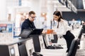 Side view of handsome man wearing glasses giving passport to staff at check in desk at airport