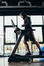 side view of handsome sportsman in hoodie running on treadmill