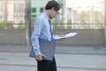 Side view of handsome young Asian business man looking paperwork or charts in his hands between walking to the office Royalty Free Stock Photo