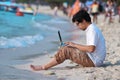 Side view of handsome young Asian man using laptop on the beach. Royalty Free Stock Photo