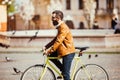 Side view of handsome young bearded man in sunglasses looking away while riding on his bicycle outdoors. Royalty Free Stock Photo