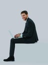 Side view of a handsome young business man sitting on a white modern chair. Royalty Free Stock Photo