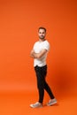 Side view of handsome young man in casual white t-shirt posing isolated on orange wall background studio portrait Royalty Free Stock Photo