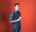 Side view of handsome young man with hand in pocket looking away and holding coffee in paper cup