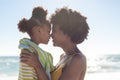 Side view of happy african american mother and daughter rubbing noses together at beach Royalty Free Stock Photo