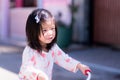 Side view of happy Asian kid riding a bicycle with a red handle. Girl smiles sweetly in the morning. Royalty Free Stock Photo