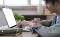 Side view happy asian man sitting in living room and surfing internet with laptop computer Royalty Free Stock Photo