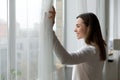 Side view happy attractive woman opening curtains. Royalty Free Stock Photo