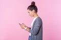 Side view of happy beautiful teenage girl using cell phone, feeling excited of chatting with friends. pink background Royalty Free Stock Photo