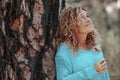 Side view of happy beautiful woman enjoying nature and outdoor leisure activity alone looking and admiring trees. Big old trunk