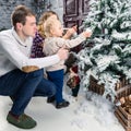 Side view of happy family decorating Christmas tree at home. Con Royalty Free Stock Photo