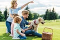 side view of happy family with pet looking away while sitting on grass