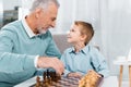 side view of happy grandson and grandfather looking at each other while playing chess Royalty Free Stock Photo