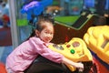 Side view of happy little Asian kid girl playing arcade video game. Motorcycle Racing