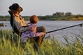 Side View On Happy Mature Man With Grandson Holding Rod While Sitting On River Bank Royalty Free Stock Photo