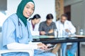 Happy female surgeon in hijab looking at camera while using digital tablet in the hospital Royalty Free Stock Photo