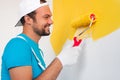Cheerful craftsman painting wall with roller
