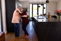 Side view of happy romantic multiracial senior couple dancing in kitchen at retirement home Royalty Free Stock Photo