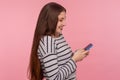 Side view of happy smiling young woman typing on cell phone, reading funny blog, chatting in social network Royalty Free Stock Photo