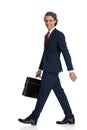 Side view of happy young businessman holding suitcase and walking Royalty Free Stock Photo