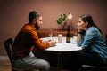 Side view of happy young couple enjoying talking and sitting together at dinner table in cozy dark living room. Royalty Free Stock Photo