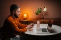 Side view of happy young man making video call using laptop computer presenting ring and making remote marriage proposal