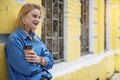 Cheerful blond girl relaxing near yellow building