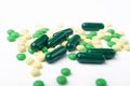 A side view of a heap of yellow and green medicine pills and capsules.