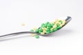 A side view of a heap of yellow and green medicine pills in a spoon. Royalty Free Stock Photo