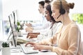 Side view of helpline operators with headsets consulting customers at modern call center, empty space Royalty Free Stock Photo