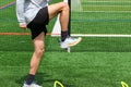 Athlete standing over small yellow hurdles on a green turf field