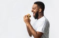 Side View Of Hungry Black Man Eating Burger, White Background