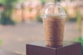 Side view Ice coffee cappuccino, latte, mocha in plastic cup with water drop on wooden column with blurry garden background with Royalty Free Stock Photo