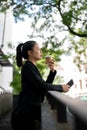 A beautiful and relaxed millennial Asian businesswoman is drinking her afternoon coffee outdoors