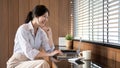 A beautiful Asian businesswoman is reading online documents on her laptop and working indoors Royalty Free Stock Photo
