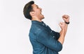 Side view image of excited young man wearing denim shirt, screaming and celebrating victory, isolated on white studio background Royalty Free Stock Photo