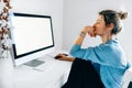 Rear view of a freelacer businesswoman using desktop computer in the office. Pretty young blonde woman sit indoors at home working Royalty Free Stock Photo