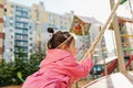 Side view image of happy pretty little girl climbing on a rope at playground outdoor. Cute preschool toddler girl playing outside Royalty Free Stock Photo