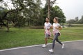 Side view image of young asian couple wearing sportswear running or jogging in park outdoor during summer season. healthy or Royalty Free Stock Photo