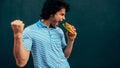 Side view image of a young handsome man eating a cheeseburger. Hungry man in a fast-food restaurant eating a hamburger outdoors. Royalty Free Stock Photo